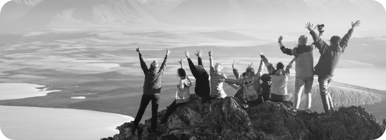 Bergsteigermannschaft auf einem Berg in schwarz-weiß, mit Armen in der Luft, Blick auf ein Tal