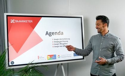 Mann zeigt auf ein Whiteboard mit der Google AdWords Coaching Agenda